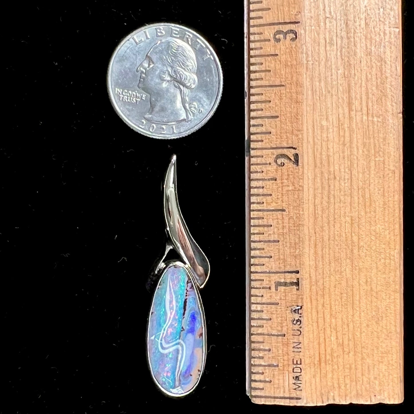 A white gold solitaire pendant set with an Quilpie, Australian boulder opal stone. The opal shines a rainbow of colors.
