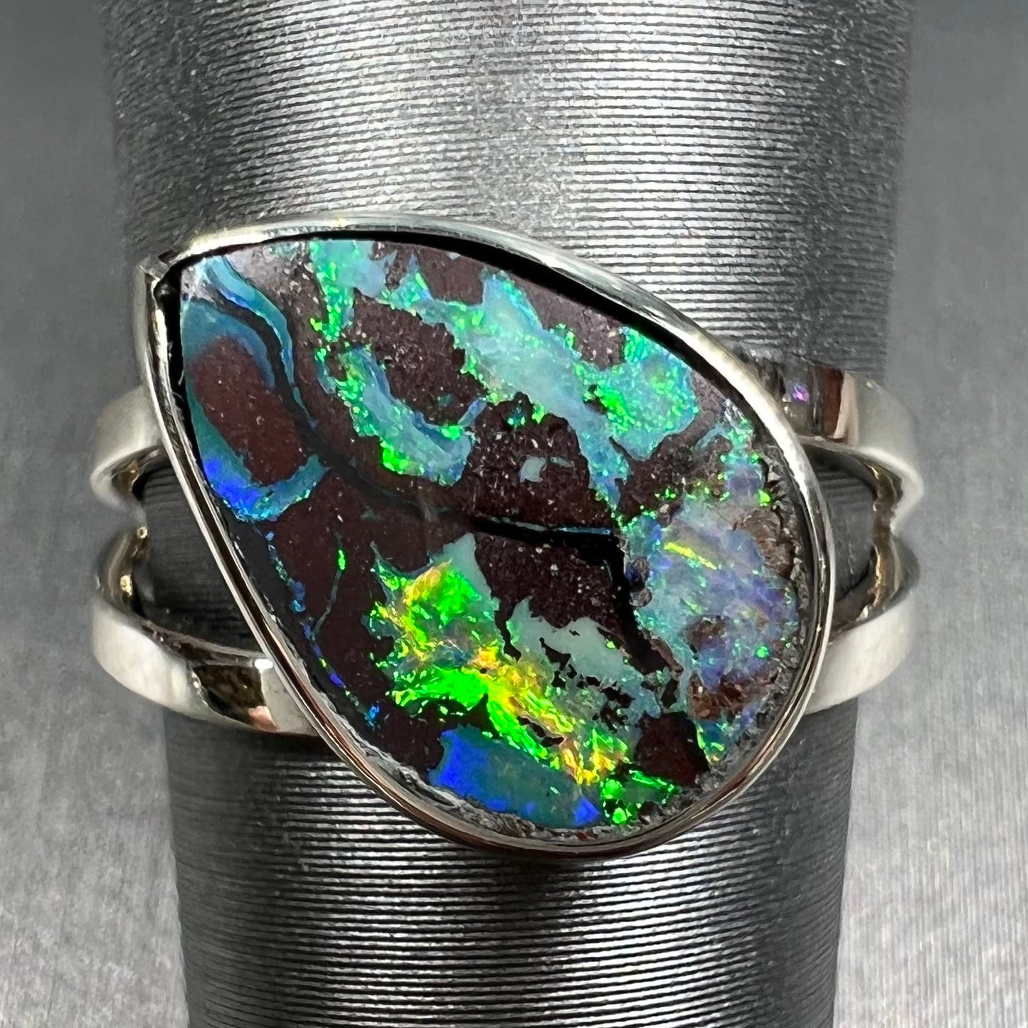 A split shank white gold boulder opal solitaire ring. The stone has a natural hematite seam that runs through it.