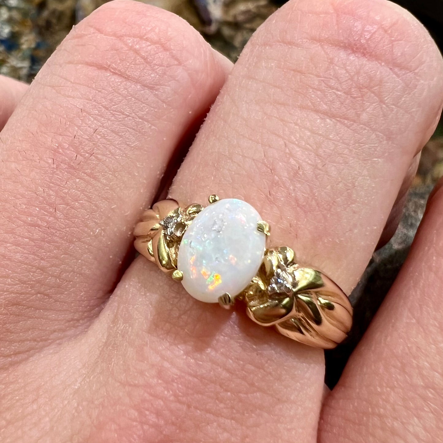 A ladies' yellow gold white crystal opal and diamond ring. The opal is prong set.
