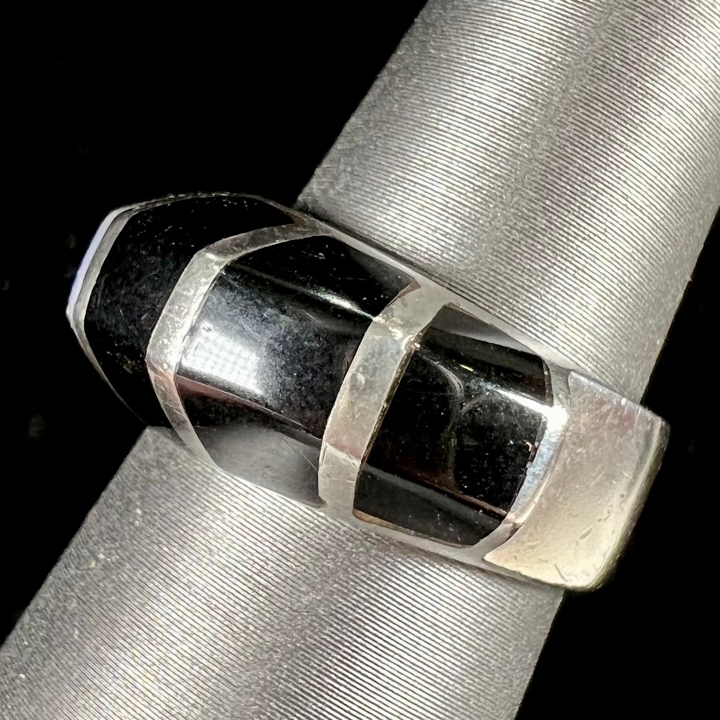 A sterling silver ring inlaid with onyx, turquoise, coral, lapis lazuli, and mother of pearl stones.