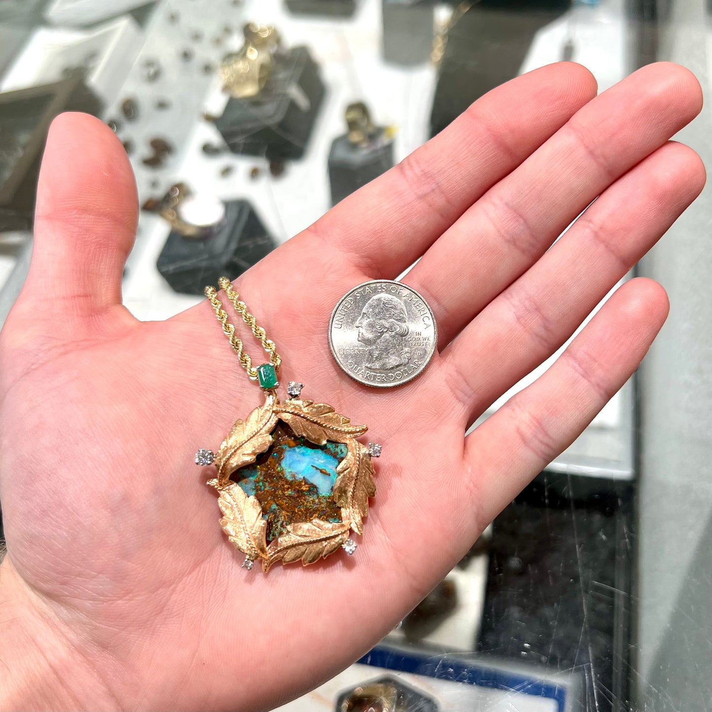 A gold opalized wood, diamond, and emerald pendant. The opal is set in a wreath of gold feathers that form a star.