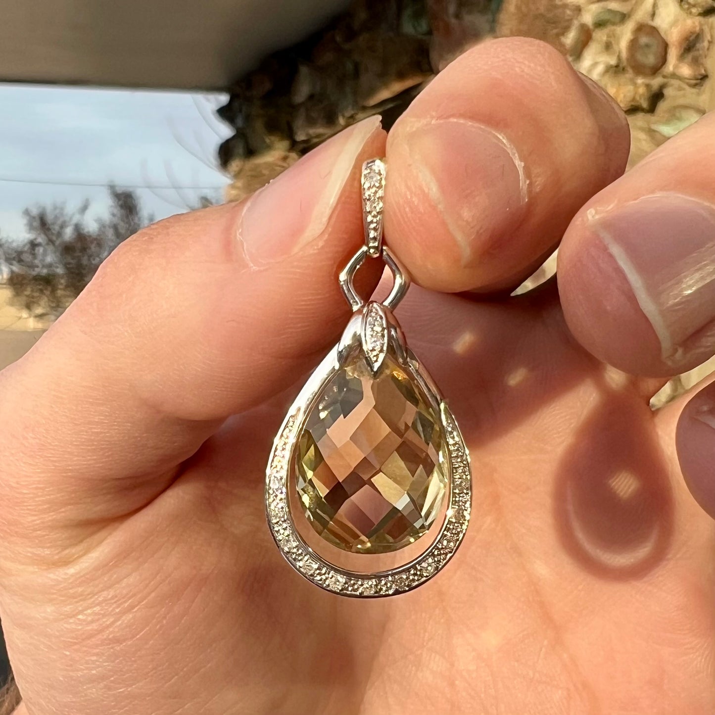 A ladies' white gold pendant set with diamonds and a faceted brilloette cut yellowish green heliodor beryl stone.