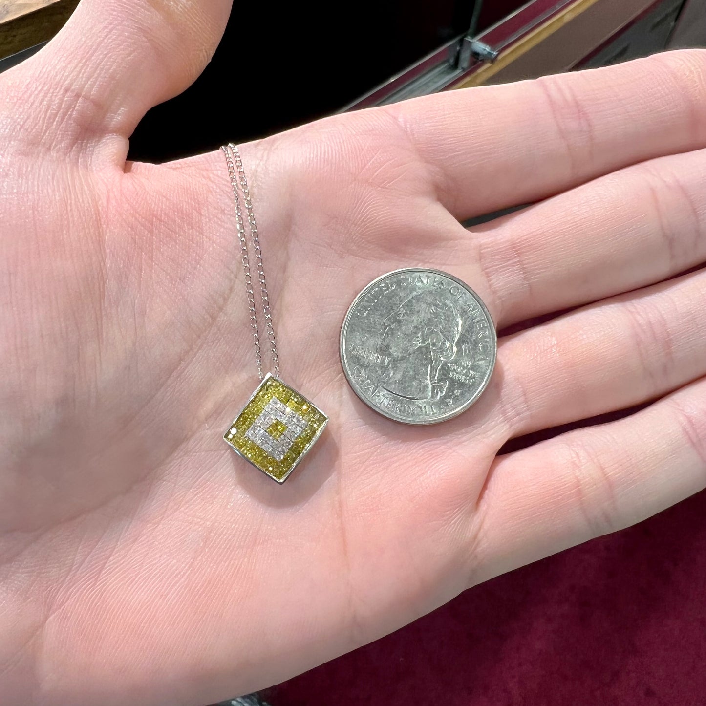 A square shaped necklace set with princess cut yellow and white diamonds in a white gold setting on a white gold chain.