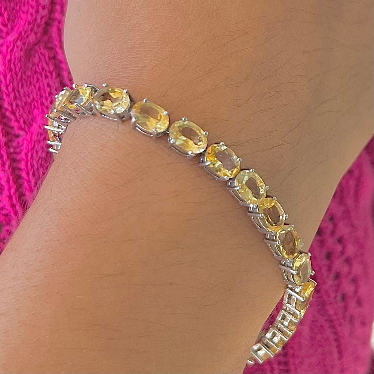A sterling silver ladies' tennis bracelet set with faceted oval cut citrine stones.