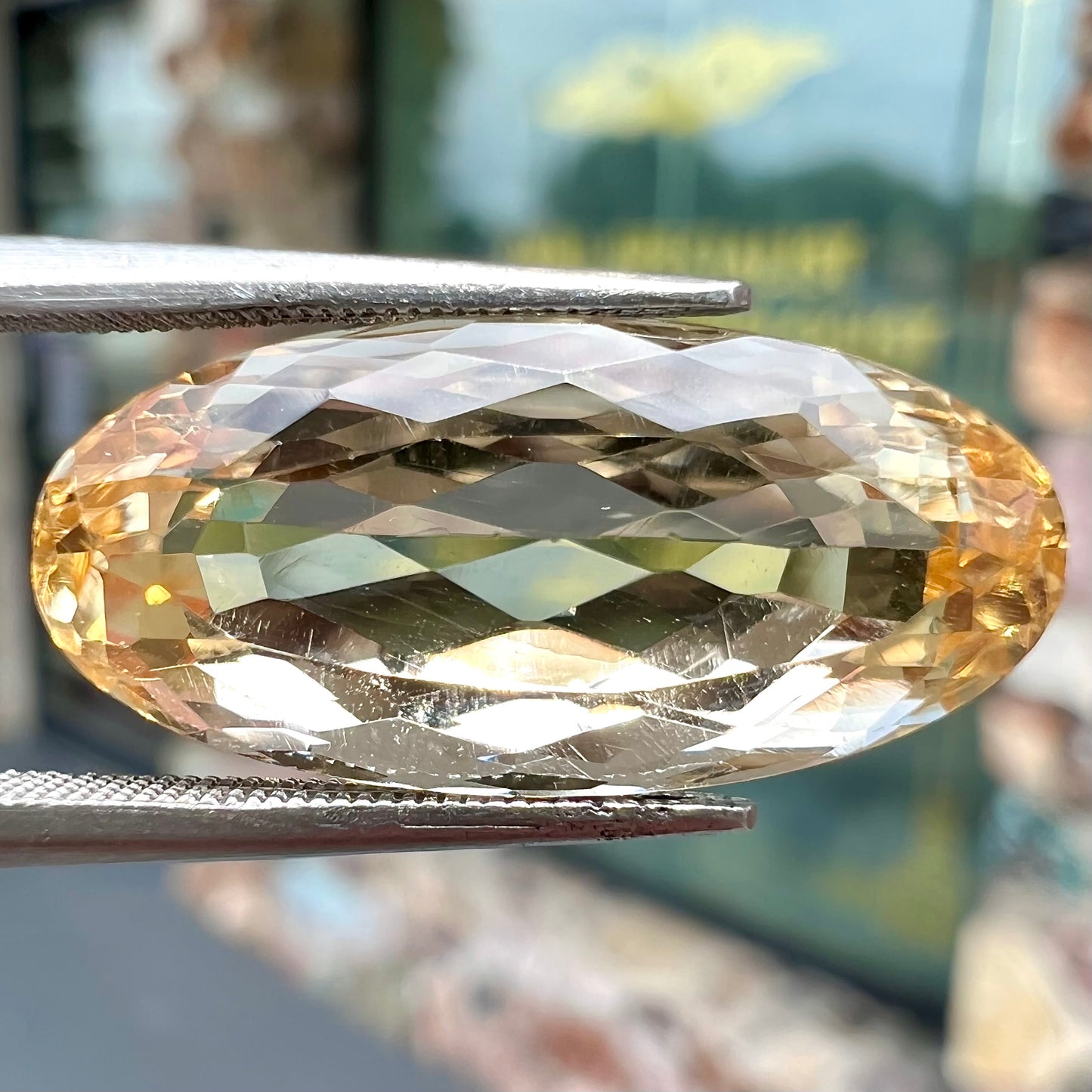 A loose, oval cut golden topaz gemstone. A stronger concentration of yellow rests in the edges of the stone.