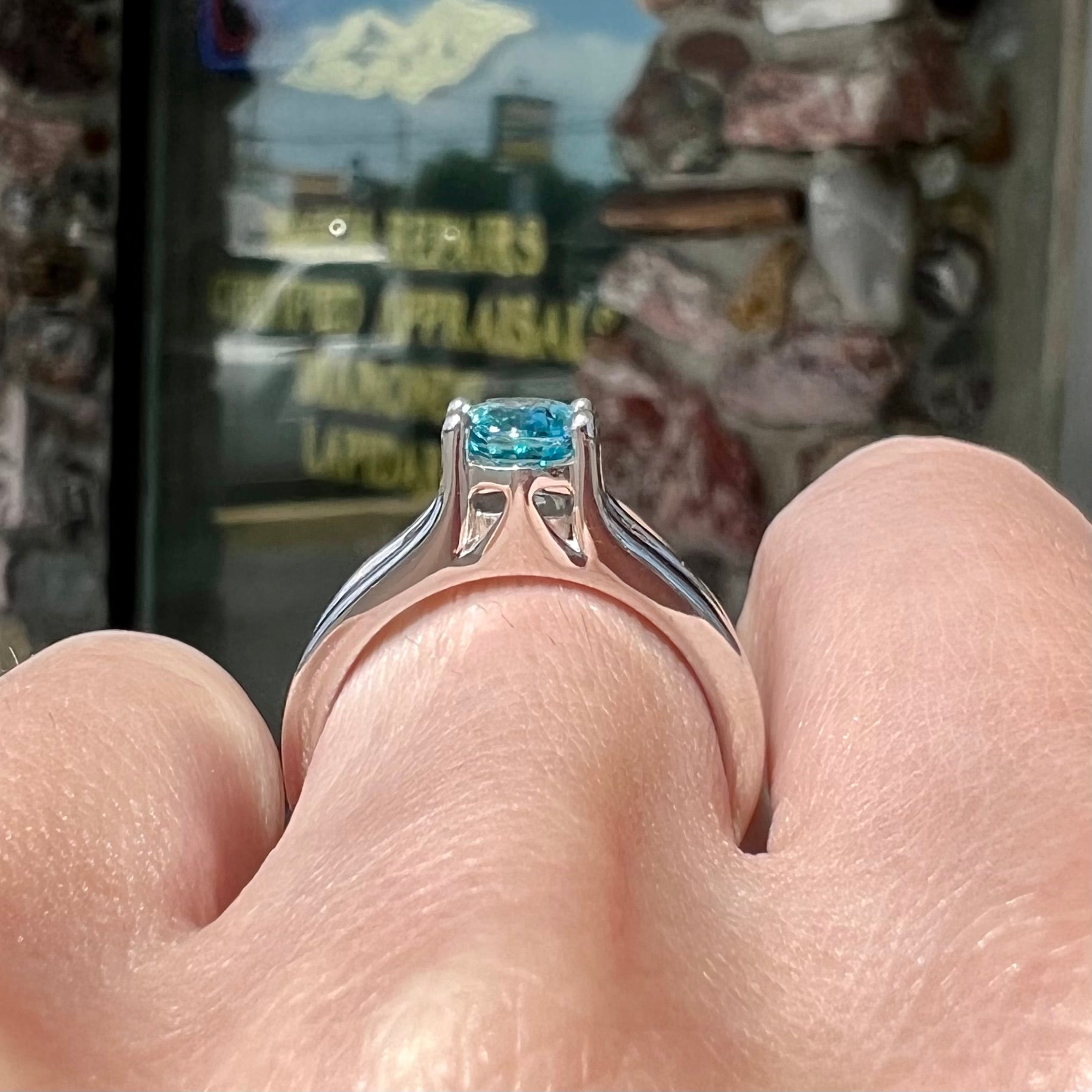 A sterling silver ring set with an oval cut blue zircon center stone and channel set white zircon accents.