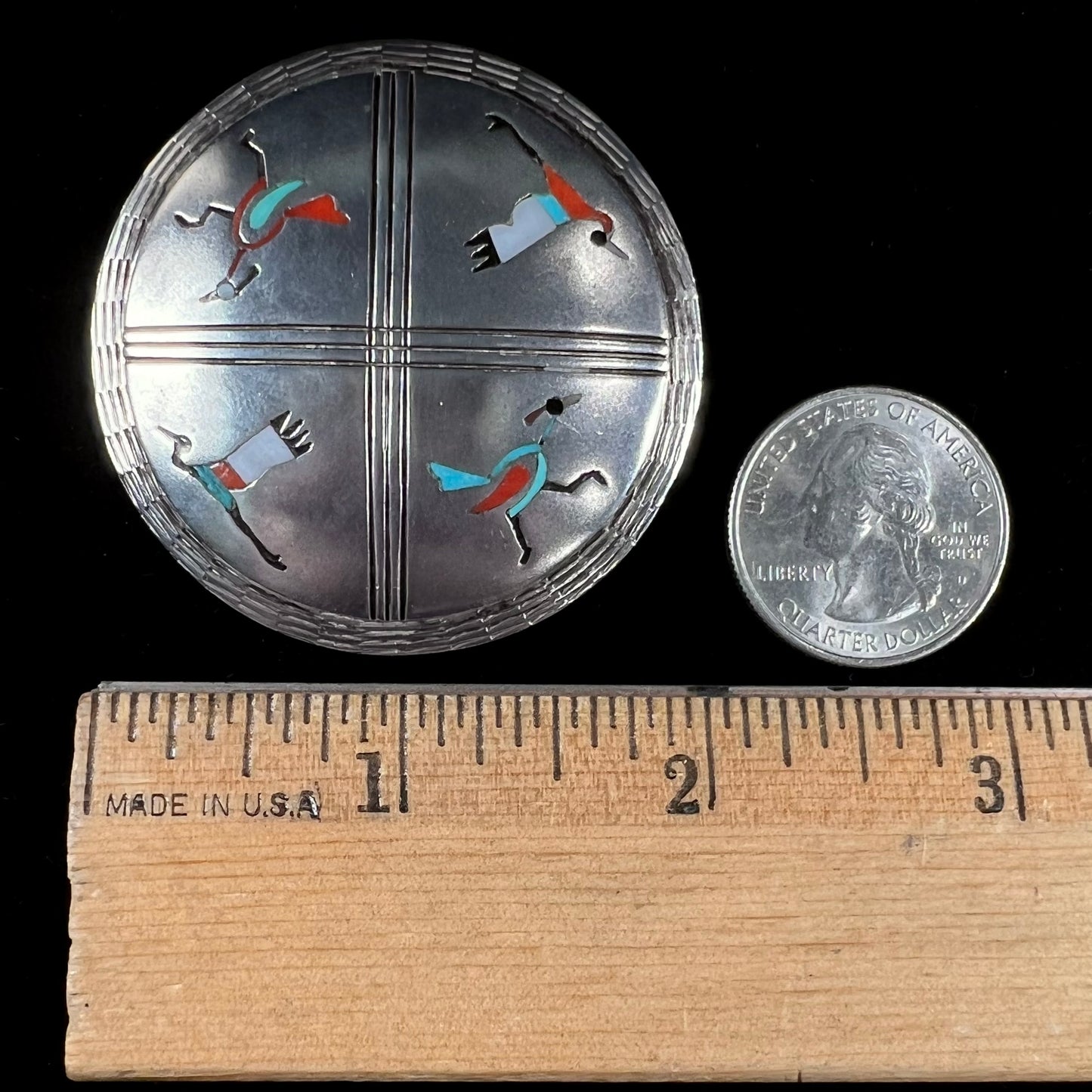 A silver pendant of two flying cranes and two roadrunners inlaid with turquoise, coral, and mother of pearl.