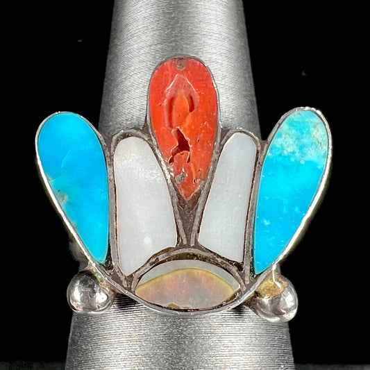 A turquoise, coral, and mother of pearl stone inlay ring made in the motif of a Zuni Indian headdress.