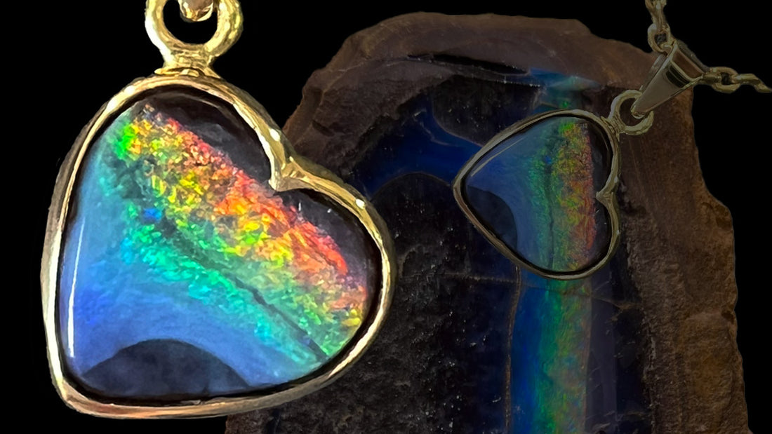 A natural boulder opal pendant in yellow gold.  The heart shaped opal shows a rainbow of colors, resembling the LGBTQ flag.