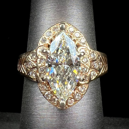 A ladies' yellow gold engagement ring set with a 1.54ct marquise cut natural diamond with round diamond accents.