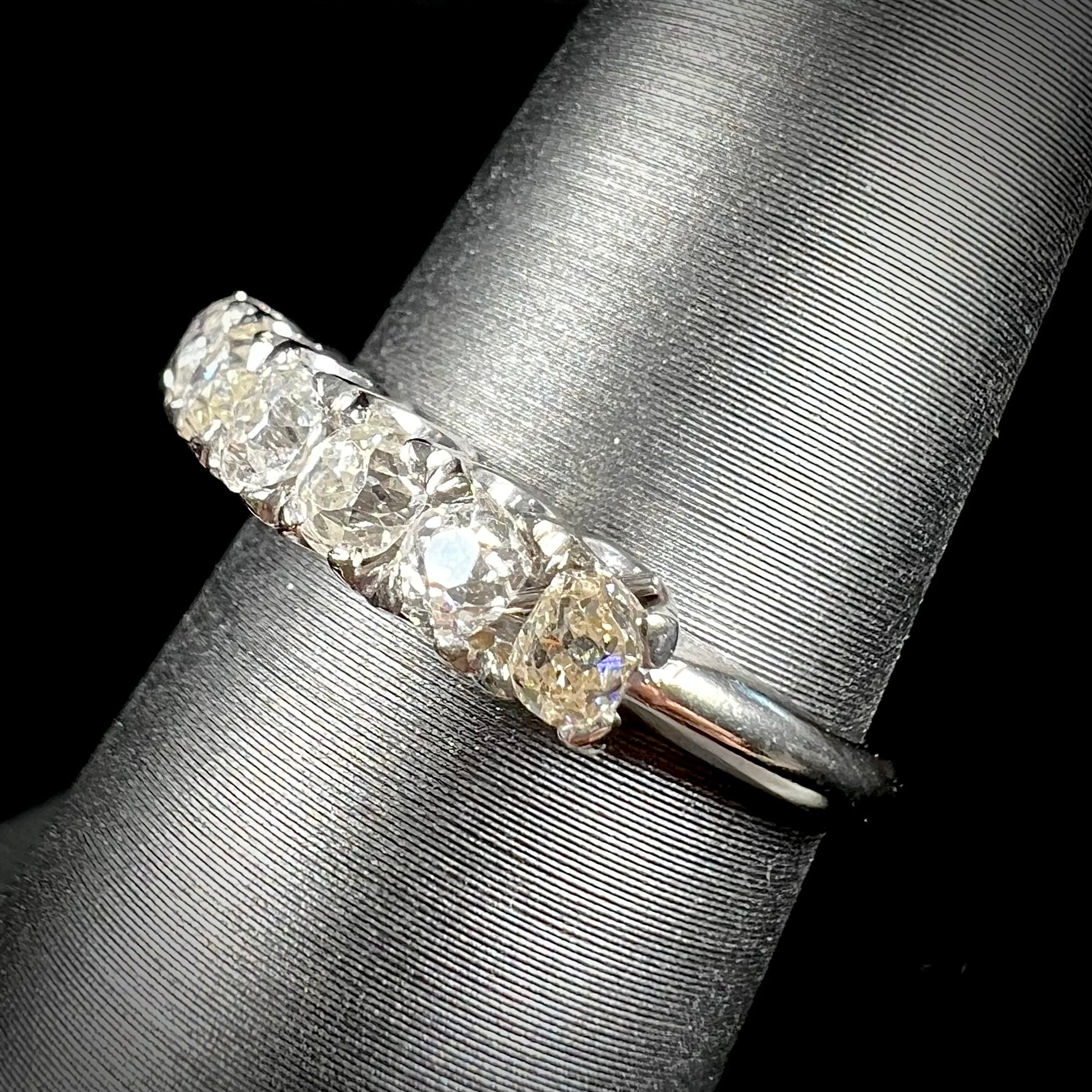An antique white gold diamond wedding band set with six old mine cut natural diamonds.