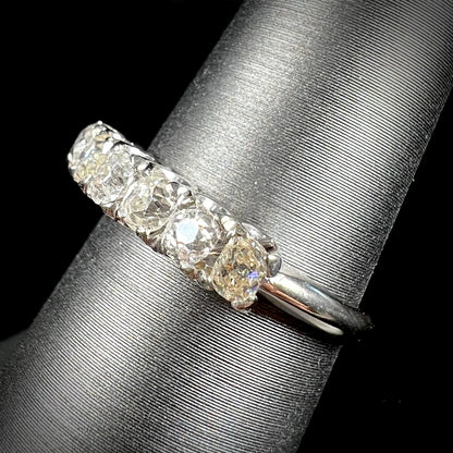 An antique white gold diamond wedding band set with six old mine cut natural diamonds.