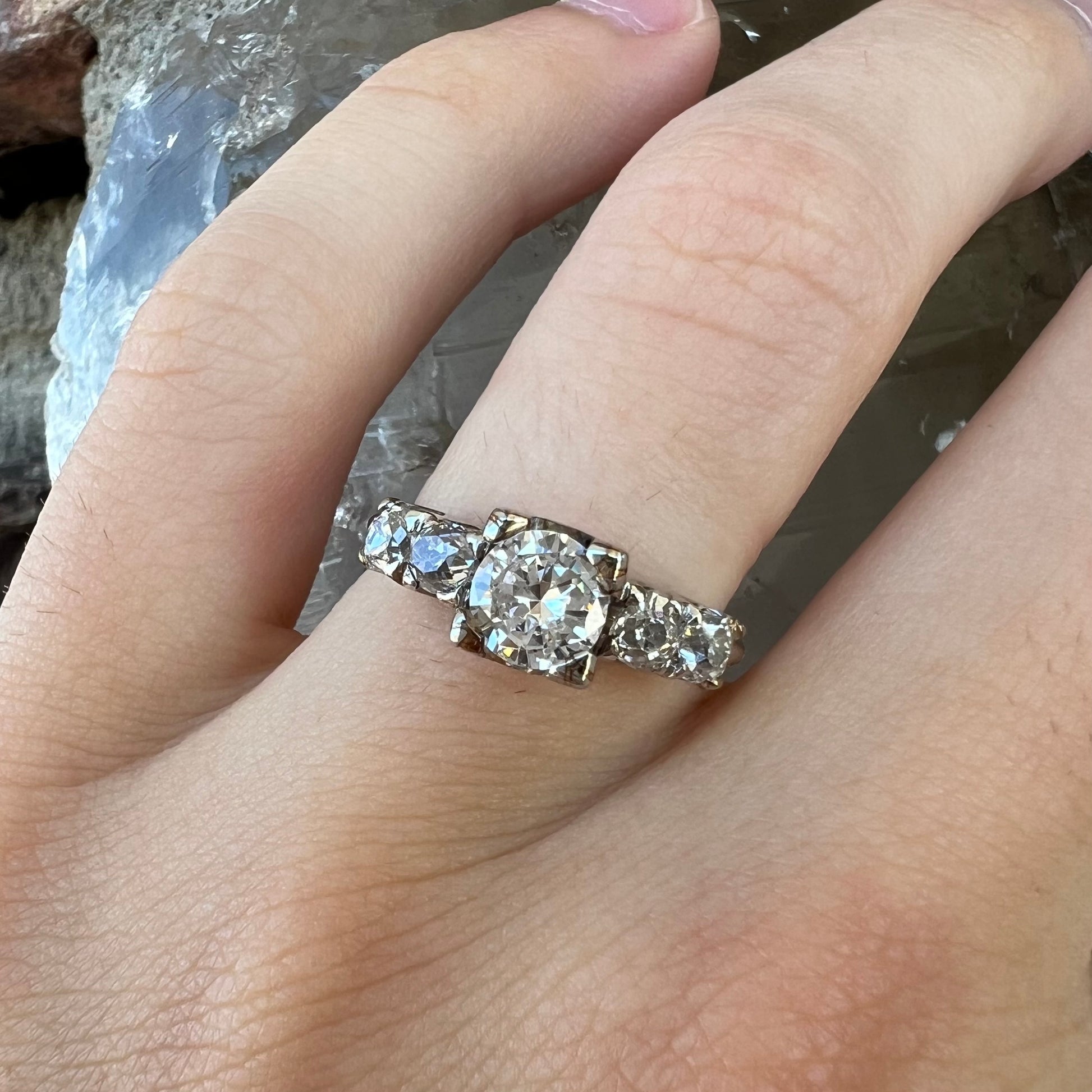 A ladies' 1800's antique white gold diamond ring.  The center stone is an Early American Cut diamond, and the accent stones are Old Mine Cut diamonds.