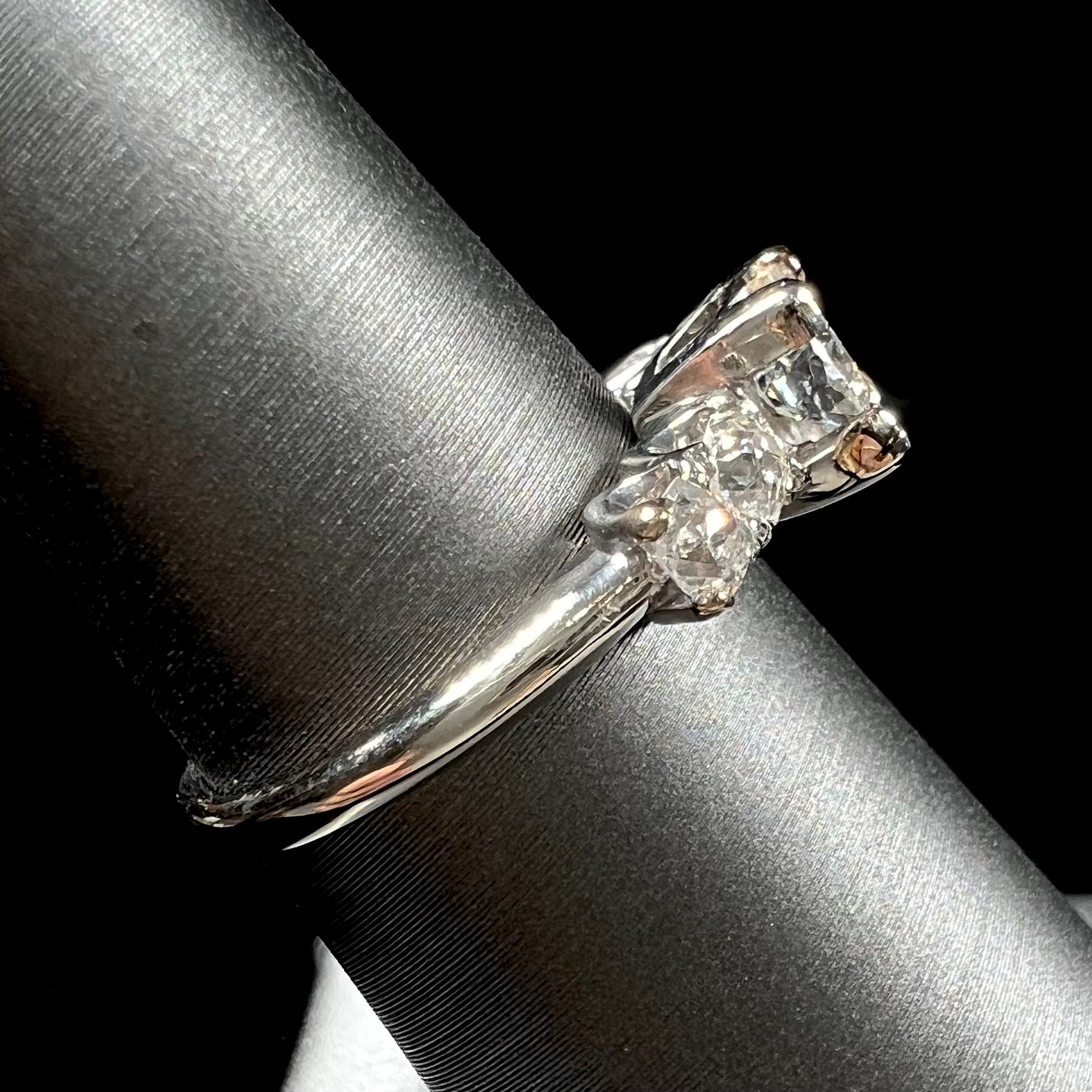 A ladies' 1800's antique white gold diamond ring.  The center stone is an Early American Cut diamond, and the accent stones are Old Mine Cut diamonds.
