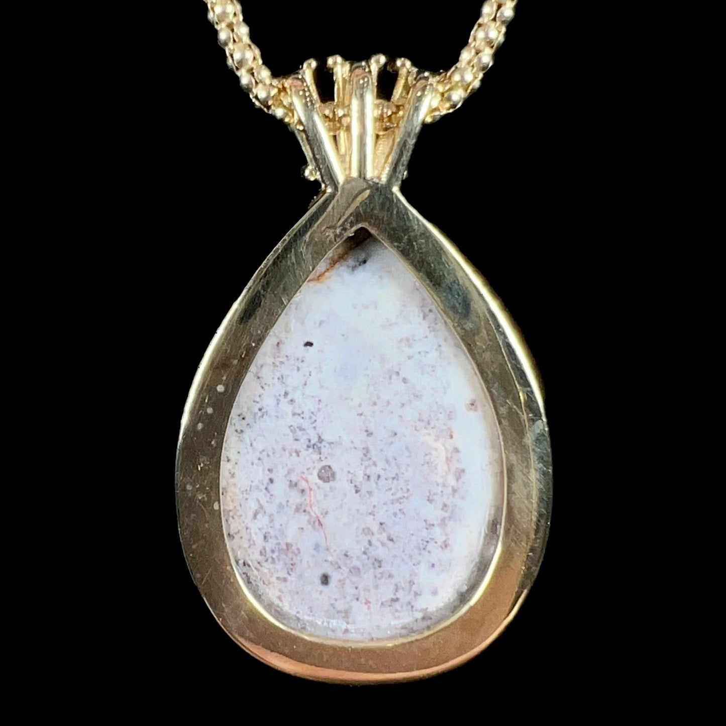 A unisex pear shaped fire opal pendant set with tapered baguette cut diamond accents in 18 karat gold.