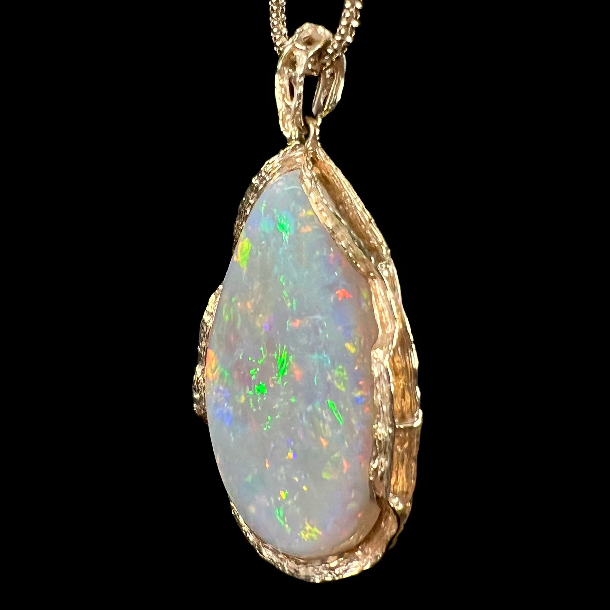 A ladies' natural, pear shaped, gray base Australian opal pendant set in 18 karat yellow gold.