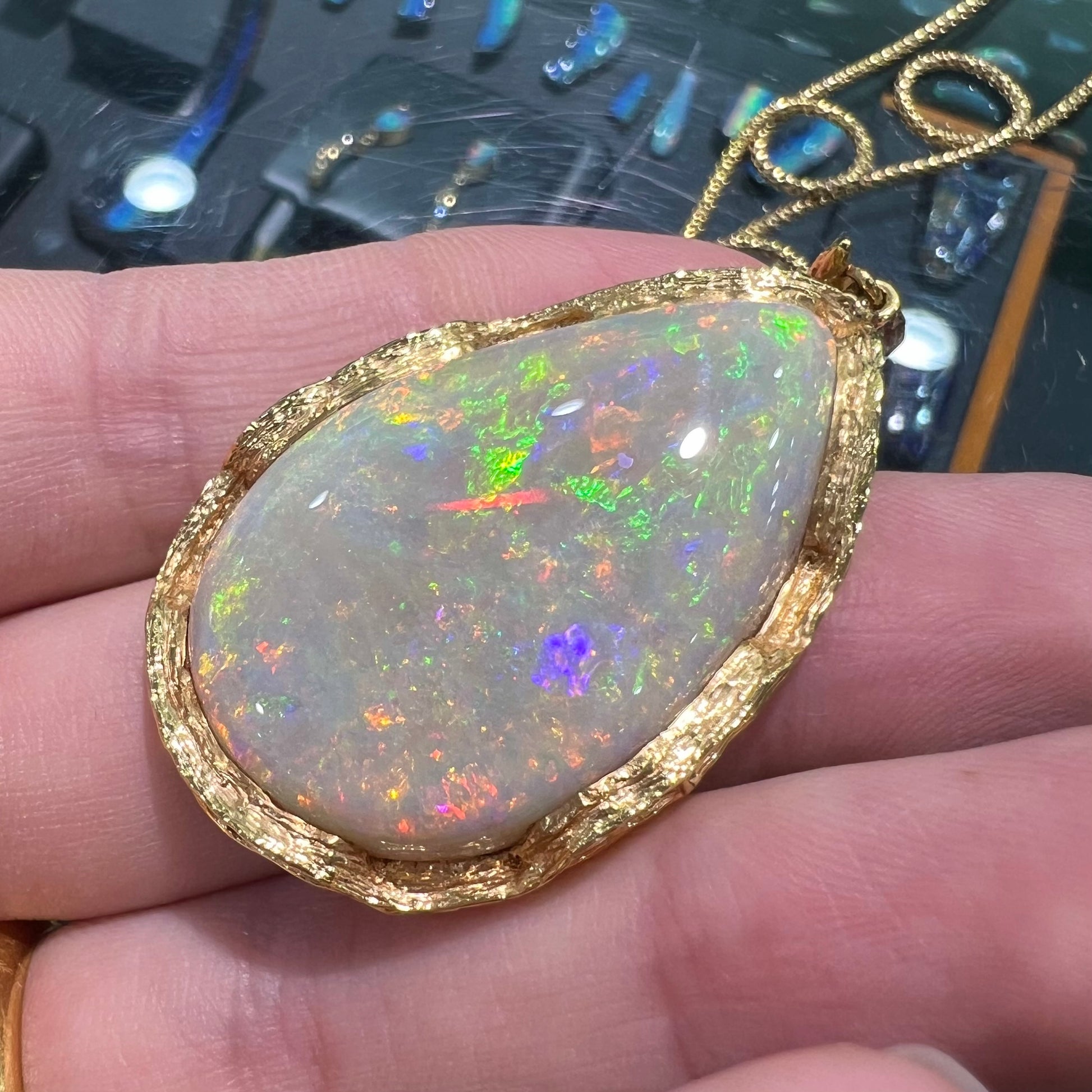 A ladies' natural, pear shaped, gray base Australian opal pendant set in 18 karat yellow gold.