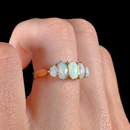 A ladies' Edwardian style 18 karat yellow gold ring set with five natural oval cut opal stones.