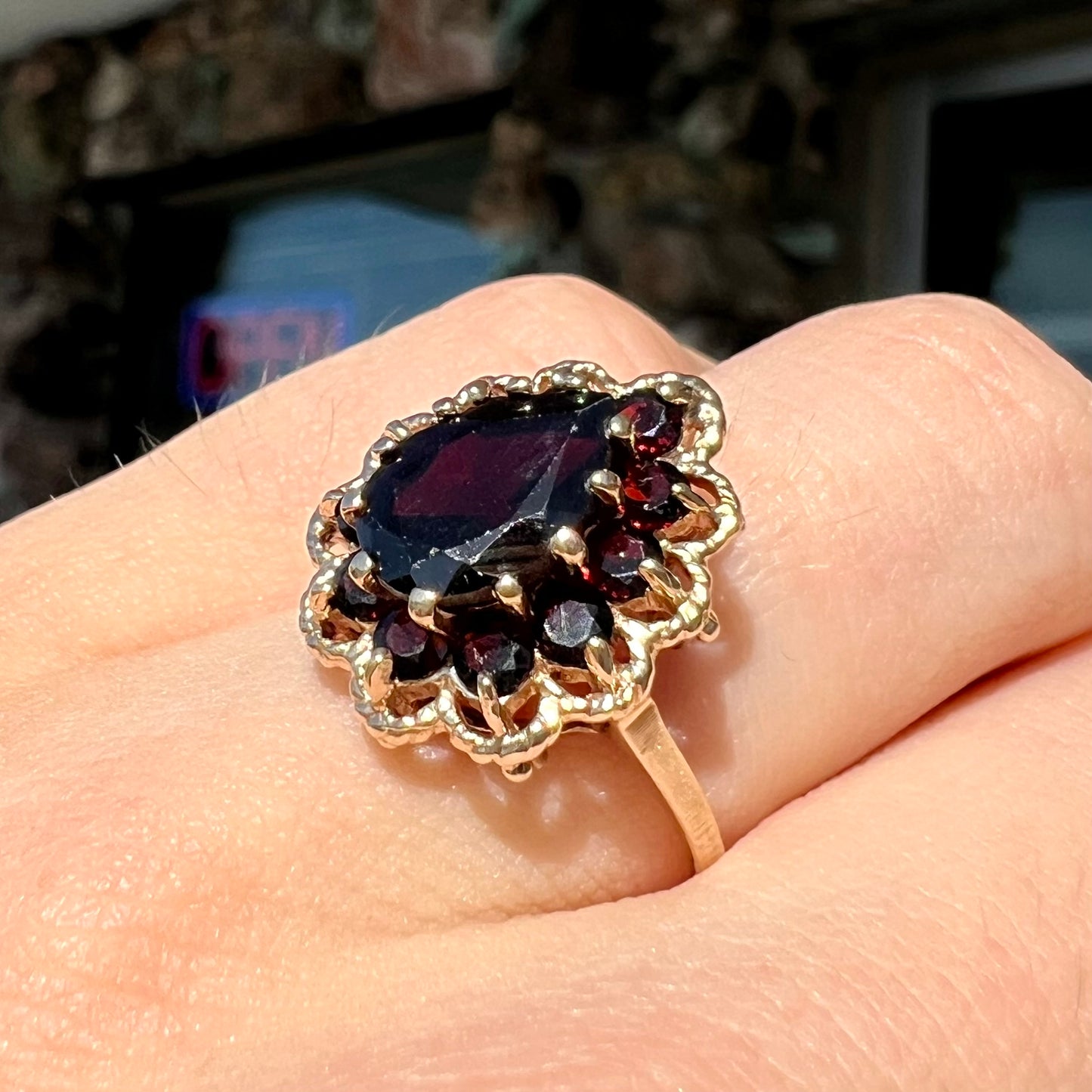 A vintage, 1940's style yellow gold ring set with a pear shaped almandine garnet.  A halo of round garnets surround the center stone.