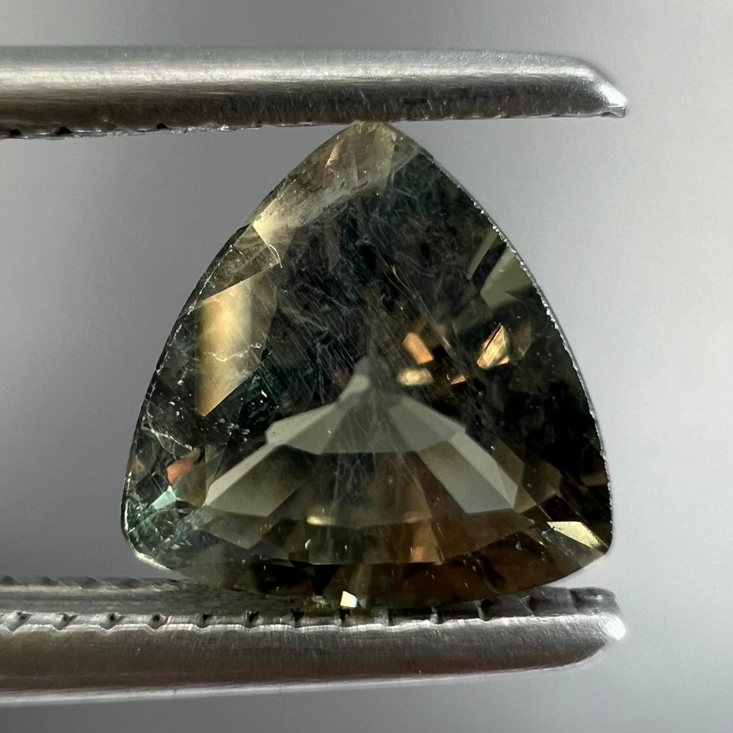 A natural, 1.10 carat, trillion cut alexandrite gemstone.  The stone changes colors from dark olive green to faint purplish green.