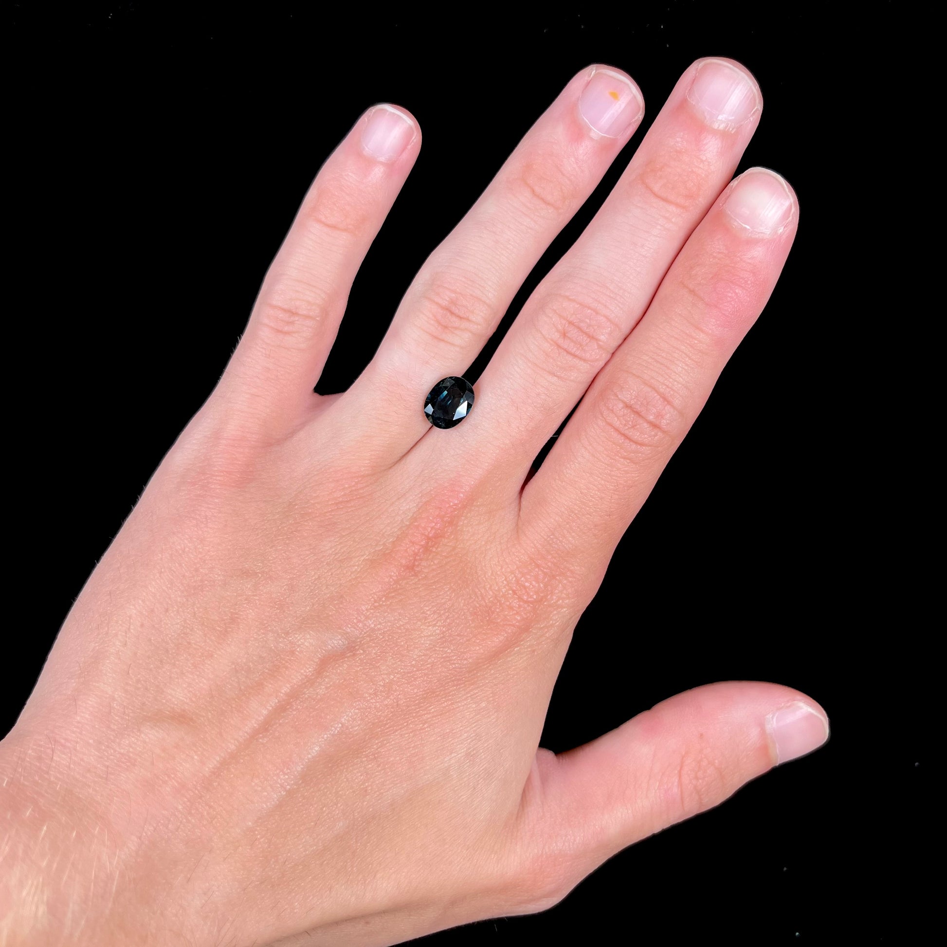A loose faceted oval cut natural sapphire.  The stone is blue-green color.