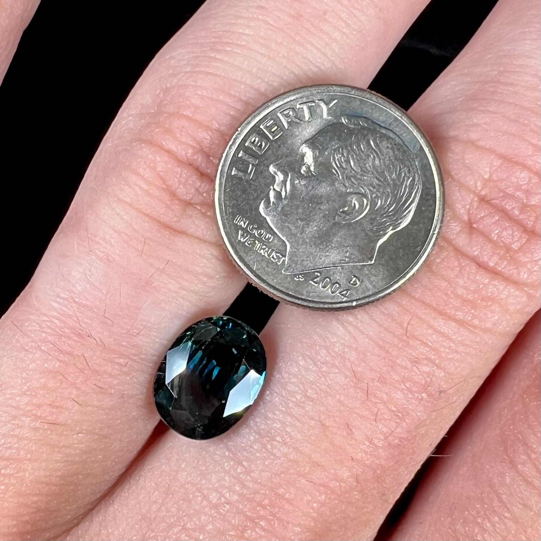 A loose faceted oval cut natural sapphire.  The stone is blue-green color.