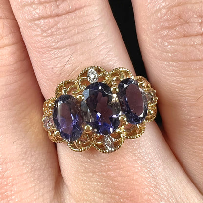 A ladies' three stone iolite ring in yellow gold set with diamond and B grade tanzanite accents.