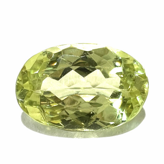 A loose, faceted oval cut chrysoberyl gemstone.  The stone is a greenish yellow color.