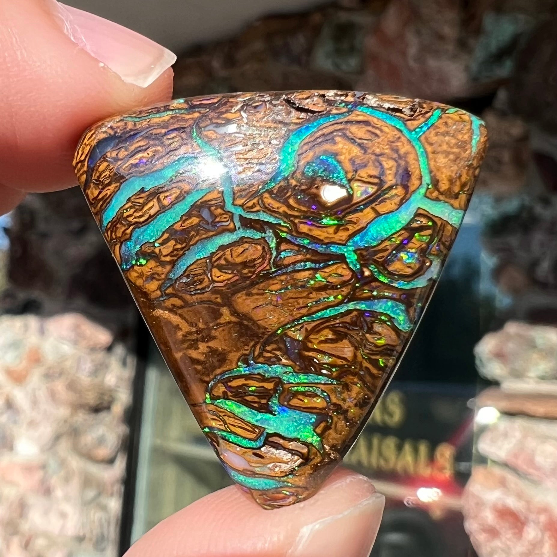 A triangle shaped Koroit boulder opal.  The stone has blue veins of opal running through it.