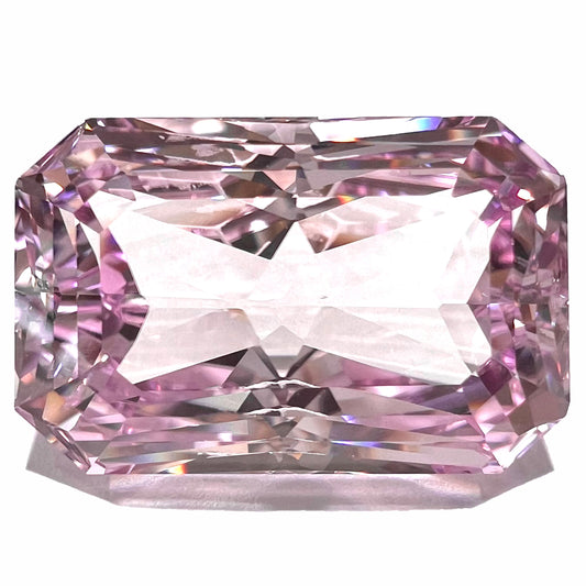 A loose, radiant cut kunzite gemstone.  The stone is a light purplish pink color.