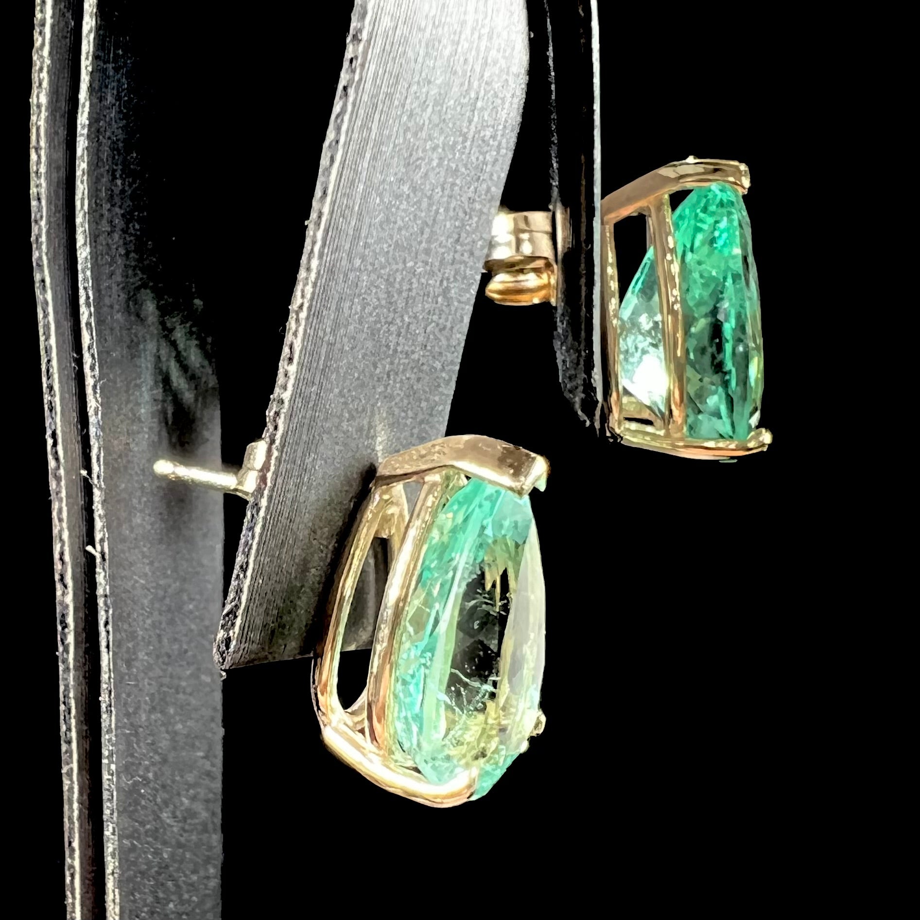 A pair of yellow gold stud earrings set with natural, pear shaped emeralds.