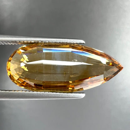 A loose, faceted briolette cut citrine gemstone.
