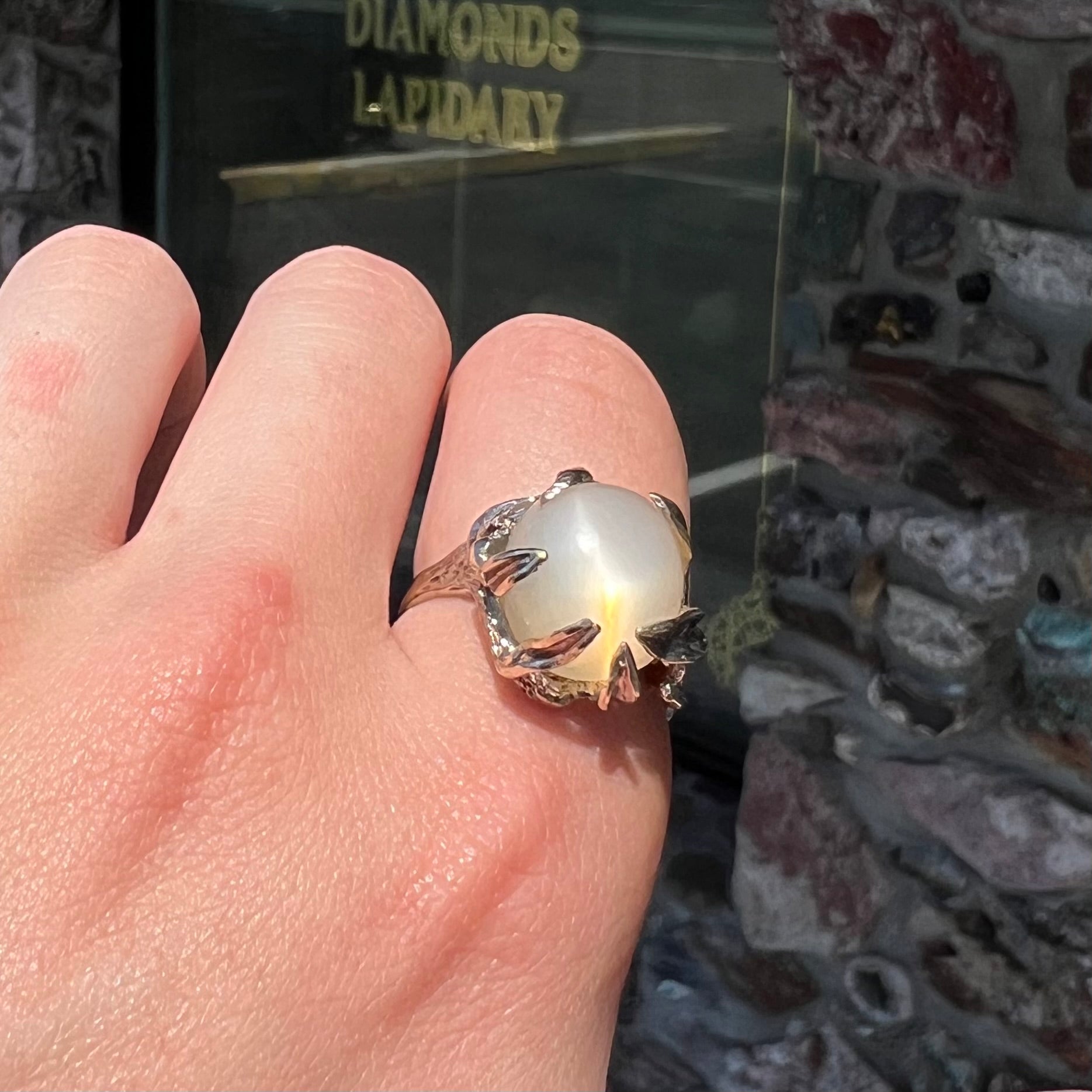 A ladies' organic style white gold moonstone ring.  The moonstone shows white adularescence on a creamy white body color.  Prongs resemble leaves holding the stone.