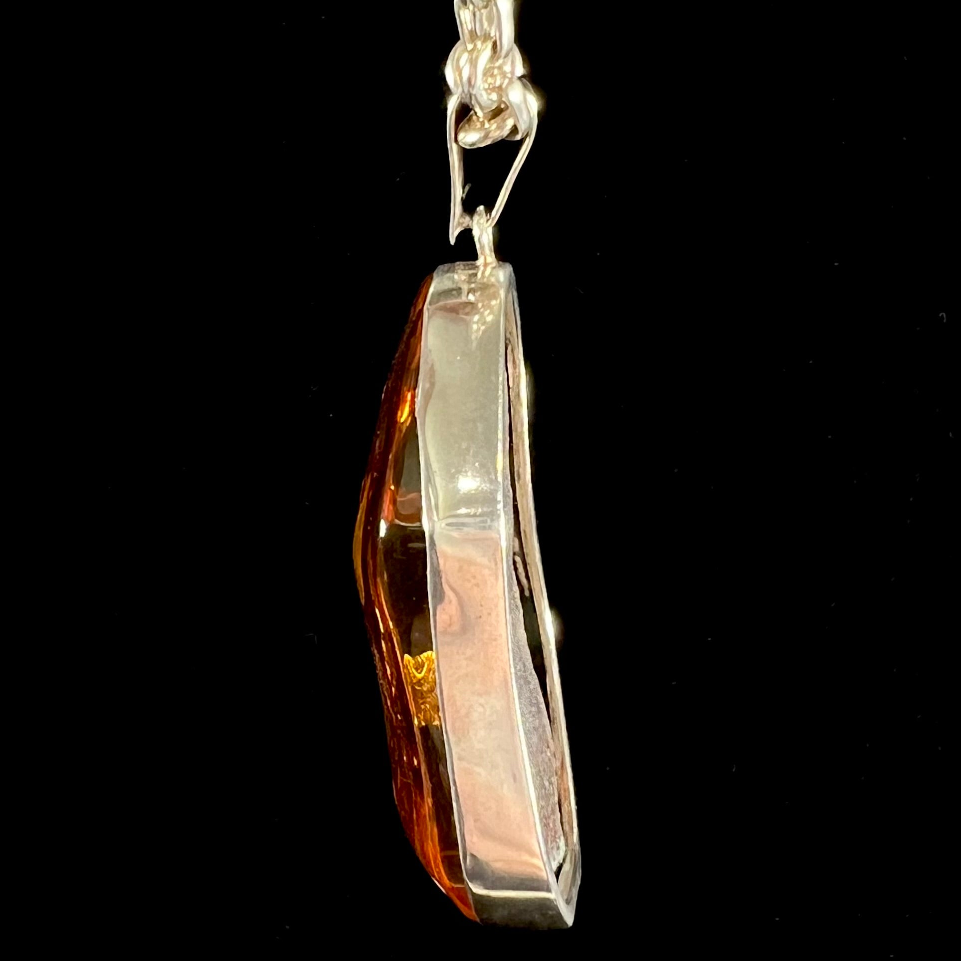 A sterling silver pendant set with a large natural amber stone.  The amber has sun spangled inclusions.