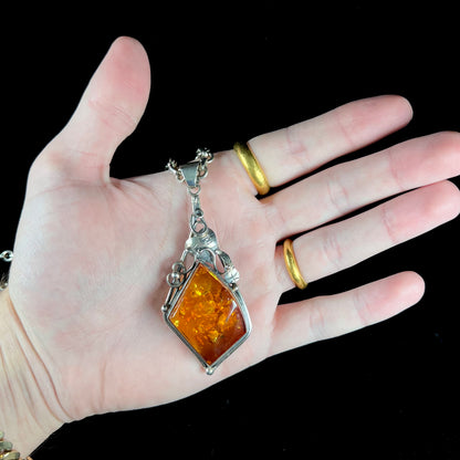 Unisex silver pendant set with a sun-spangled Mexican amber stone, featuring silver leaf design accents.
