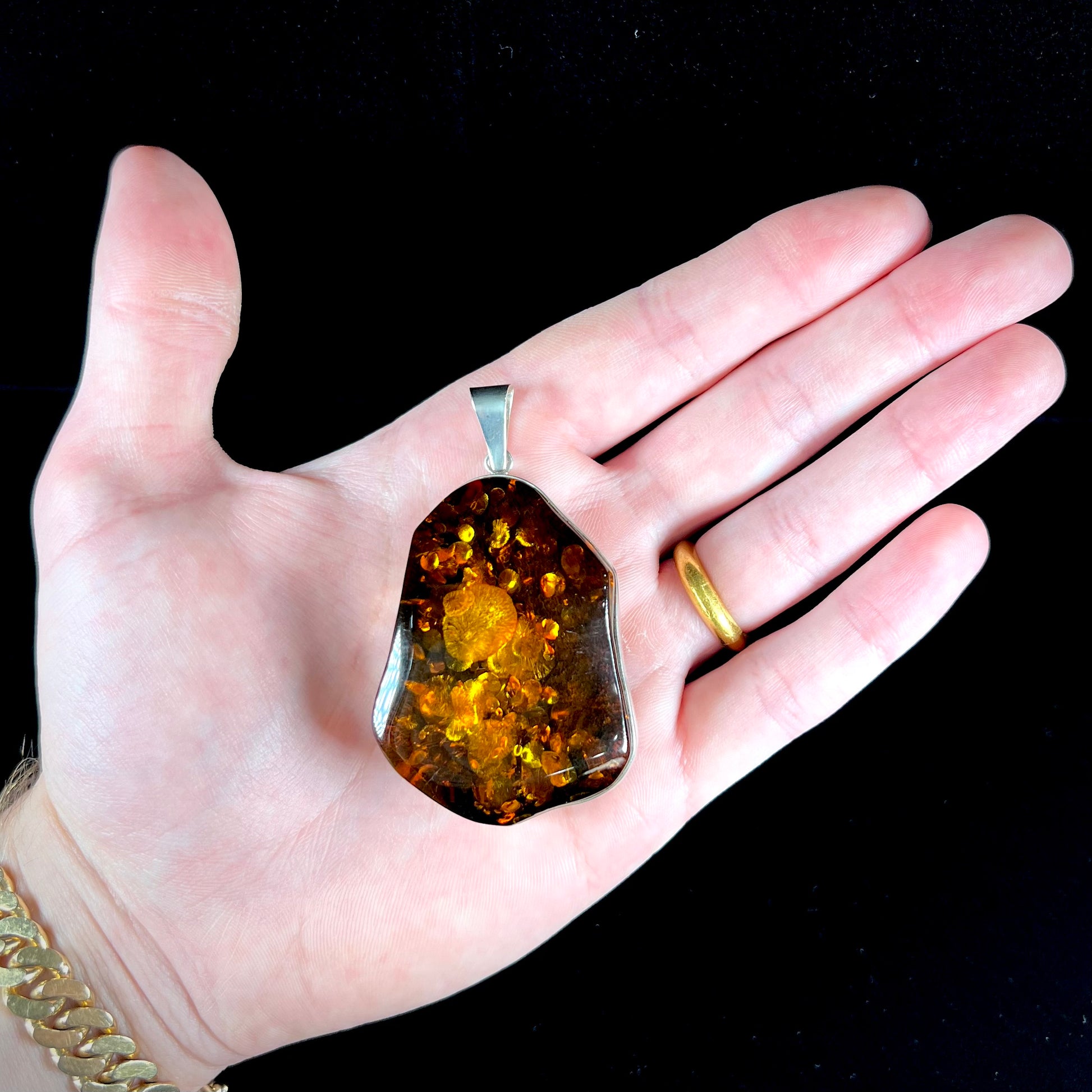 A sterling silver pendant set with a large natural amber stone.  The amber has sun spangled inclusions.
