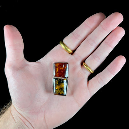 A sterling silver pendant brooch set with a red orange amber and a yellow sun-spangled amber.