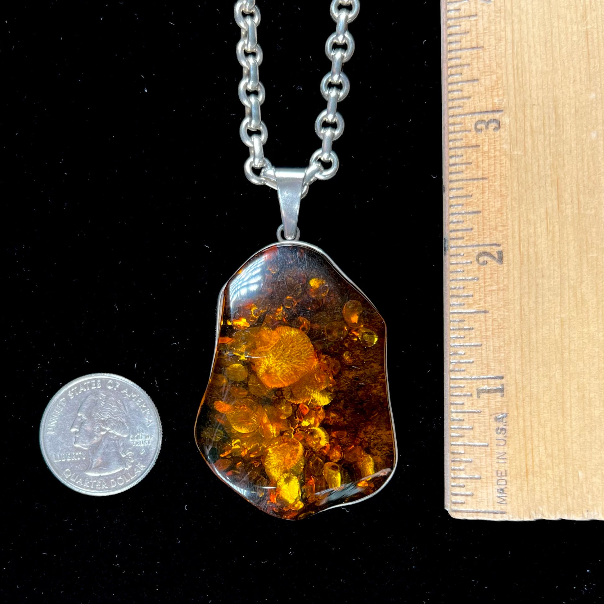 A sterling silver pendant set with a large natural amber stone.  The amber has sun spangled inclusions.