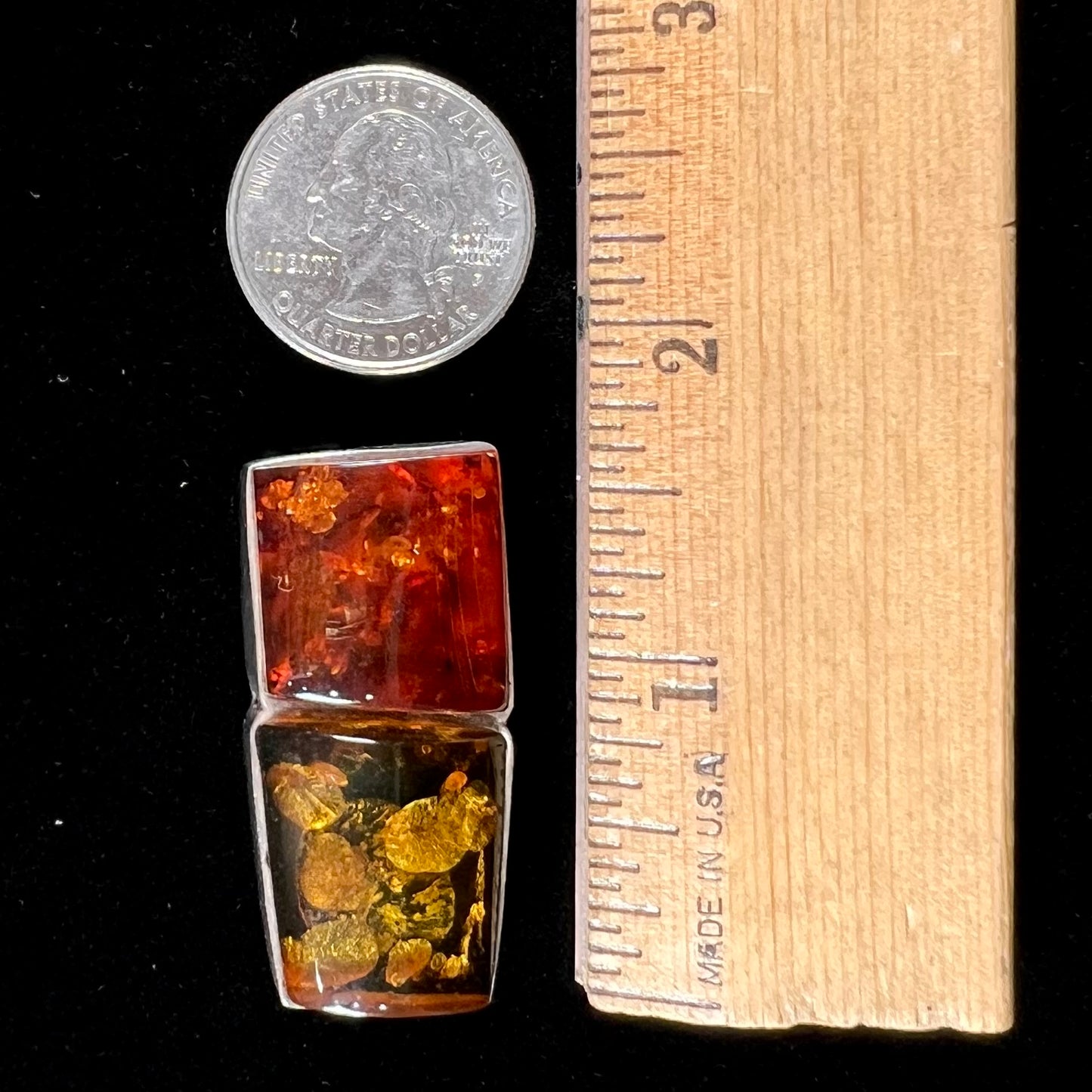 A sterling silver pendant brooch set with a red orange amber and a yellow sun-spangled amber.