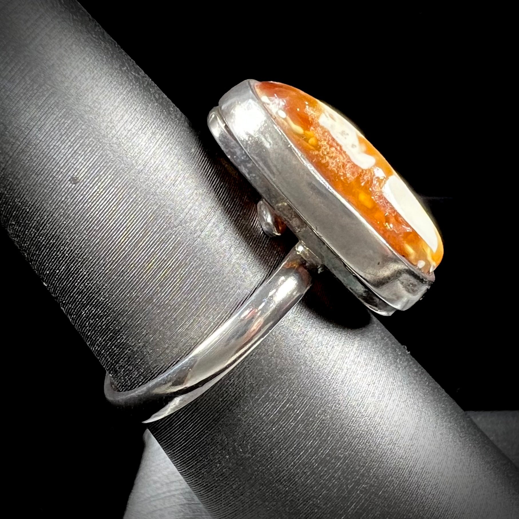 An adjustable sterling silver solitaire ring set with a cabochon cut butterscotch amber stone.