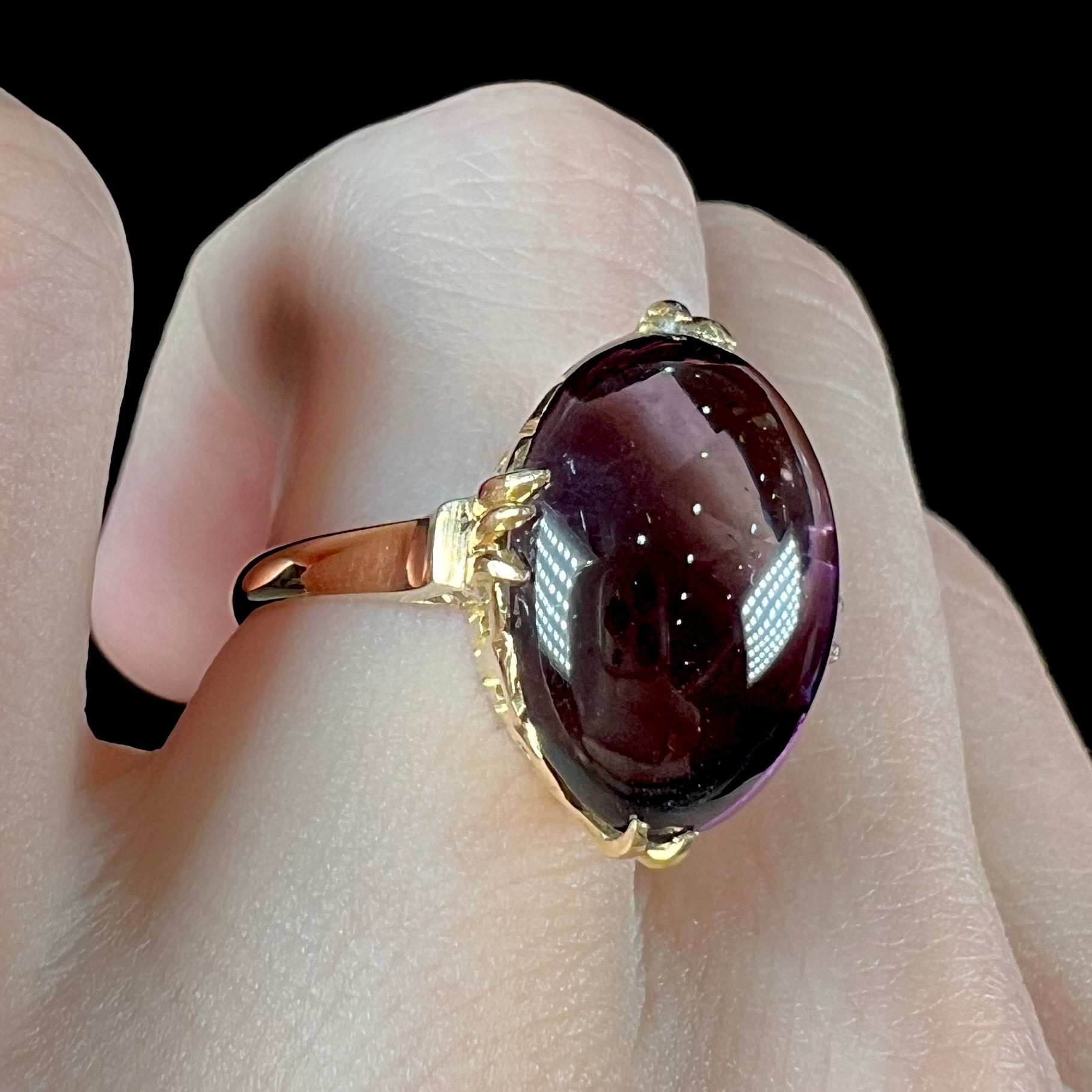 A ladies' 18 karat yellow gold oval cabochon cut amethyst ring.  The ring is 1920's style.