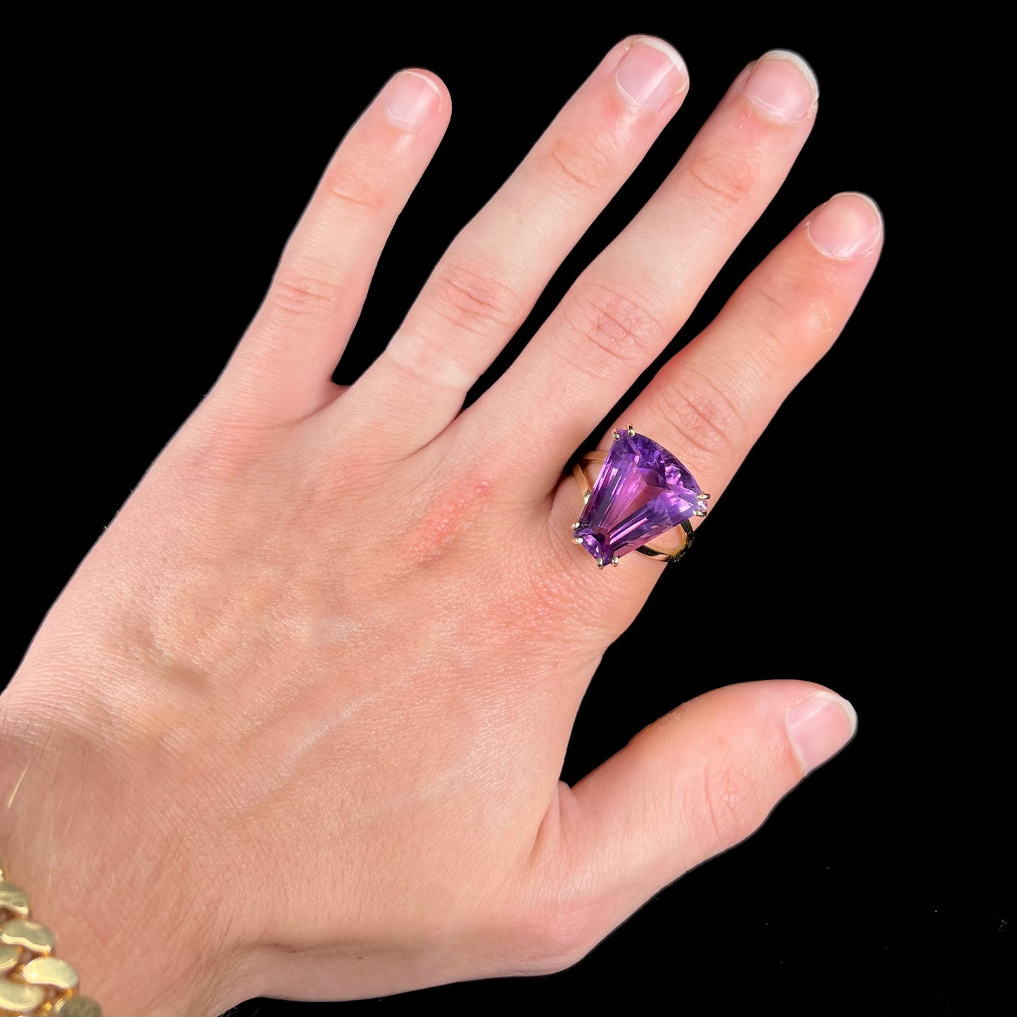 A ladies' yellow gold cocktail ring set with a shield cut purple amethyst gemstone.