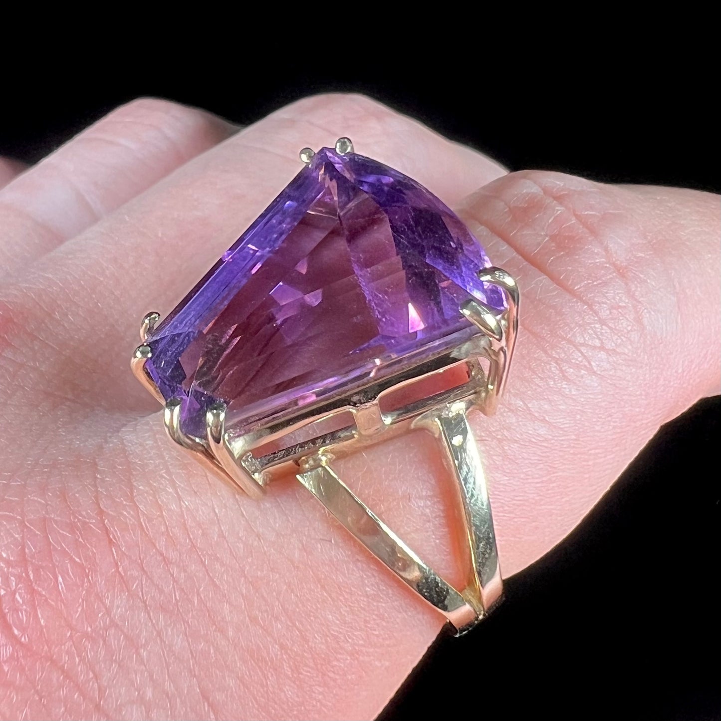 A ladies' yellow gold cocktail ring set with a shield cut purple amethyst gemstone.