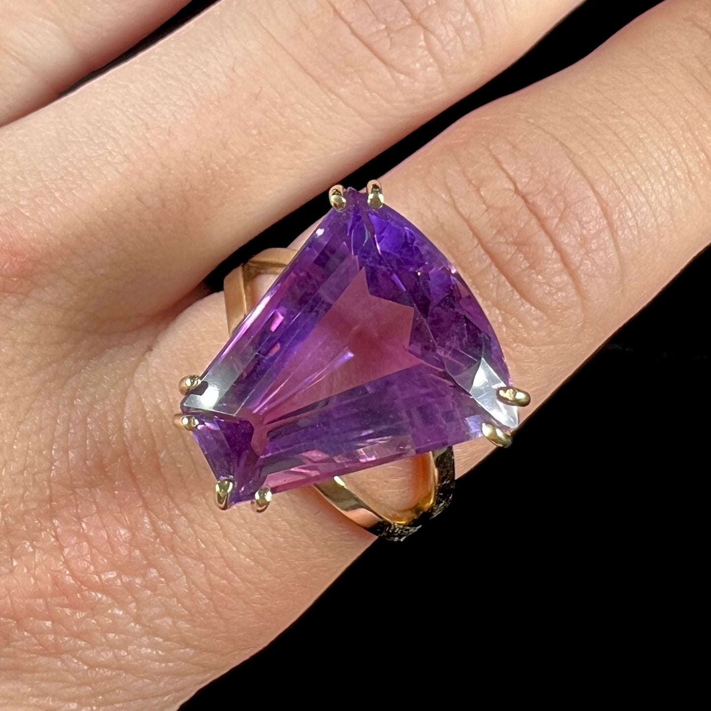 A ladies' yellow gold cocktail ring set with a shield cut purple amethyst gemstone.