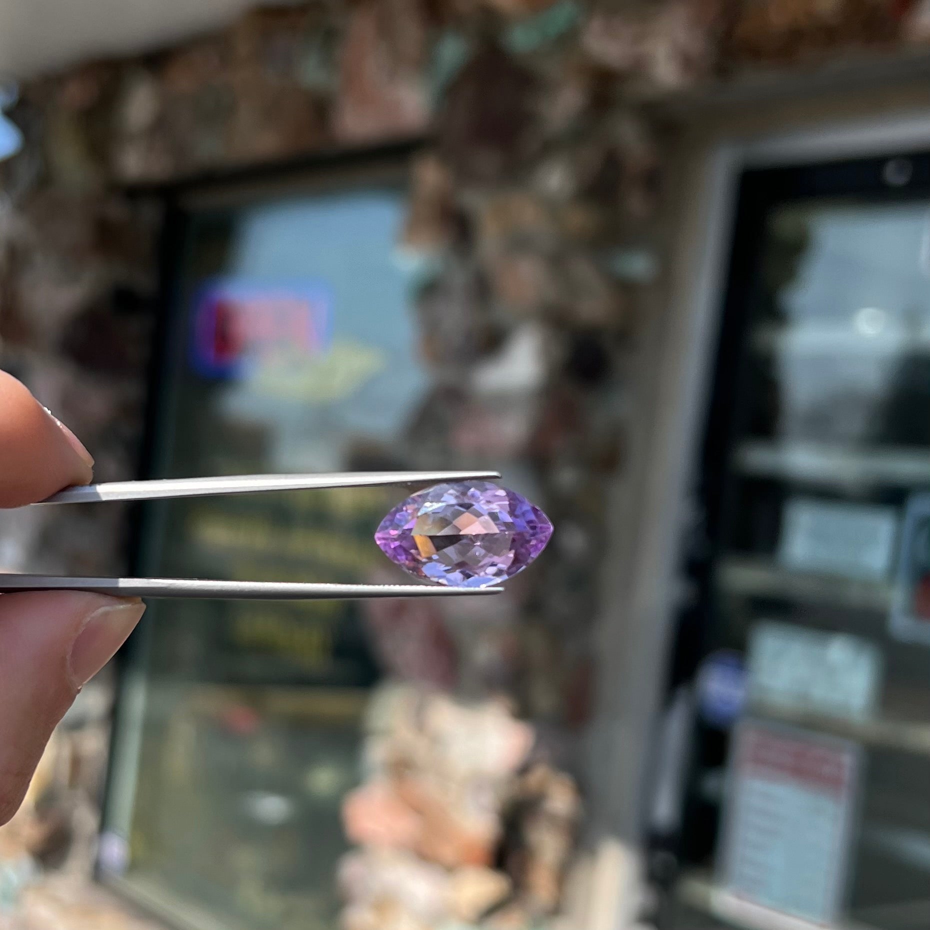 A loose marquise cut amethyst gemstone.  The stone is a light purple color and has scratches along the surface.