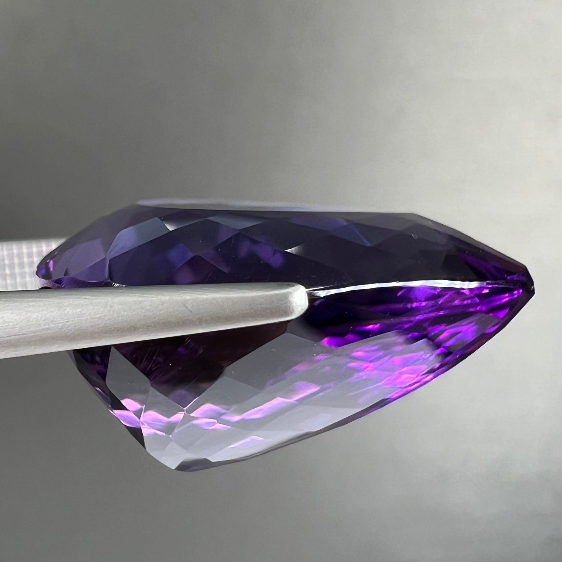 A large, pear shaped amethyst gemstone.  The stone is a dark purple color.