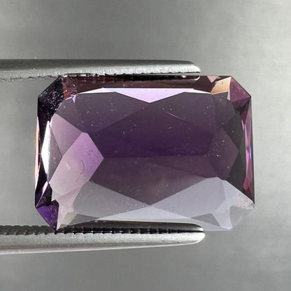 A loose, modified radiant cut amethyst stone.