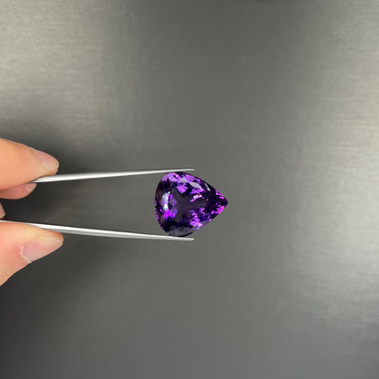 A large, pear shaped amethyst gemstone.  The stone is a dark purple color.