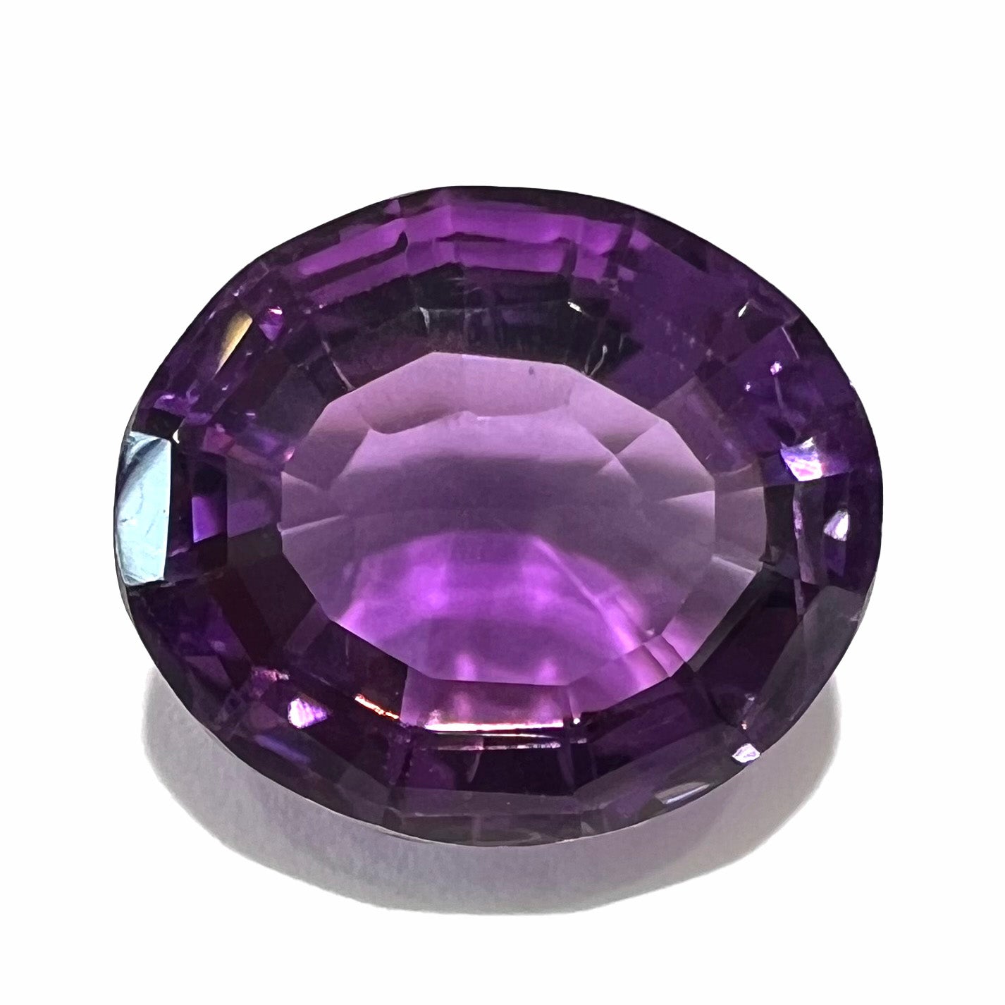 A loose, modified oval cut purple amethyst gemstone.
