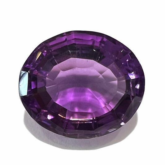A loose, modified oval cut purple amethyst gemstone.